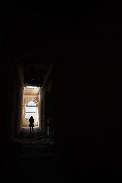 istock A man at the end of a dark corridor inside an abandoned building. 1202959708