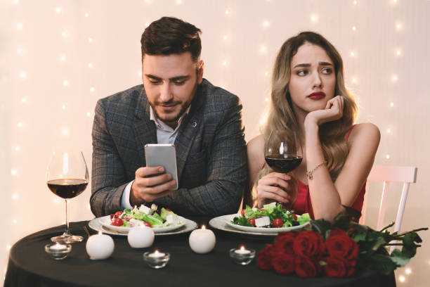 istock Boring Date. Man using smartphone in restaurant, ignoring his sad girlfriend 1202961294