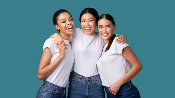 istock Three Happy Diverse Girls Hugging On Turquoise Studio Background, Panorama 1202962866
