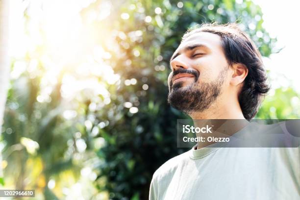 A Bearded Man Is Meditating Outdoor In The Park With Face Raised Up To Sky And Eyes Closed On Sunny Summer Day Concept Of Meditation Dreaming Wellbeing Healthy Lifestyle Stock Photo - Download Image Now