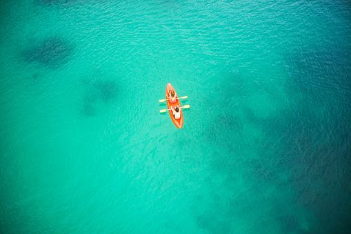 High angle shot of an adventurous young couple canoeing together in the beautiful oceans of Indonesia