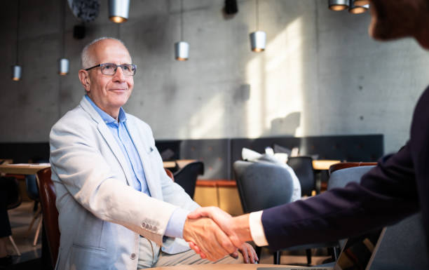 istock Senior businessman shaking hands during meeting in cafe 1202968238