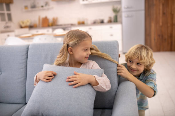 istock Boy pulling girls ponytail from behind, teasing and feeling joyful 1202968387