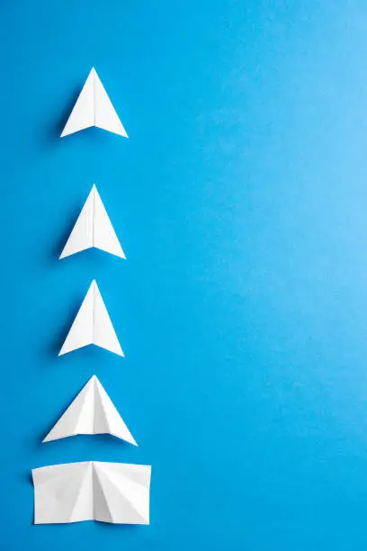 Photo of Concept of progress process with space for text. Agile evelopment attainment, motivation, growth concept. Business concept of goals, success, achievement and challenge. White paper airplanes under construction on blue background.