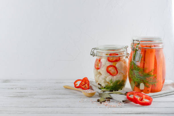 istock two glass jars of fermented cauliflower, carrots. vegetables on a light background. using textile light gray. fermentation is a source of probiotic. copy space 1202971923