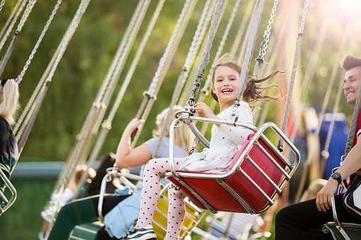 Little girl having fun on chain carousel. Happy summer memories. Carefree childhood and happiness