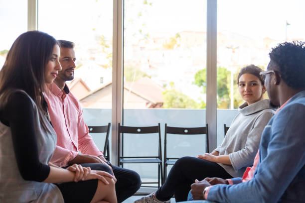 istock Cheerful co-workers sitting on chairs and talking 1202972625