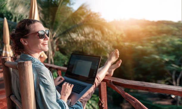 young business woman working at the computer in cafe on the rock. young girl downshifter working at a laptop at sunset or sunrise on the top of the mountain to the sea, working day. - day to sunset imagens e fotografias de stock