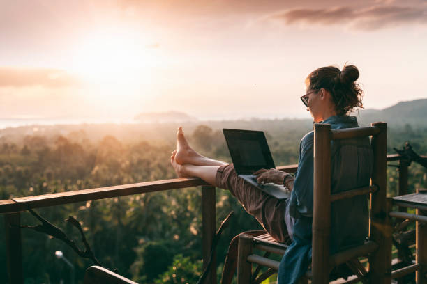 junge geschäftsfrau arbeitet am computer im café auf dem felsen. junges mädchen downshifter arbeiten an einem laptop bei sonnenuntergang oder sonnenaufgang auf der spitze des berges zum meer, arbeitstag. - liberation stock-fotos und bilder