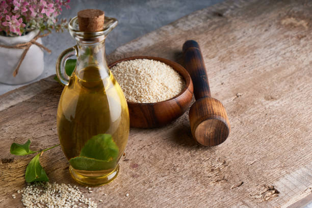 Healthy Sesame oil in glass bottle and sesame seeds on wooden background Copy space Rustic stock photo