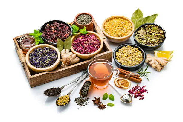 Herbal tea. Tea cup with a large variety of dried herbs and flowers for preparing healthy detox infusions isolated on white background. The composition includes dried part of plants like hibiscus, calendula, rose petals, chamomile, green tea, bay leaves, cinnamon sticks, ginger, lemons, mint leaves, a honey jar and dried orange slices among others. High resolution 42Mp studio digital capture taken with Sony A7rii and Sony FE 90mm f2.8 macro G OSS lens