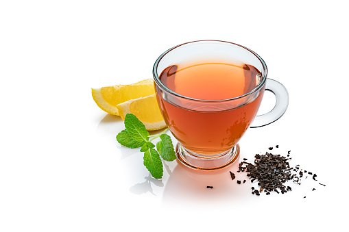 Black tea cup isolated on white background. Lemon slices and a mint twig complete the composition. The composition is at the right of an horizontal frame leaving useful copy space for text and/or logo at the left. High resolution 42Mp studio digital capture taken with Sony A7rii and Sony FE 90mm f2.8 macro G OSS lens