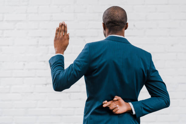 back view of african american diplomat standing with fingers crossed near brick wall back view of african american diplomat standing with fingers crossed near brick wall hands behind back stock pictures, royalty-free photos & images