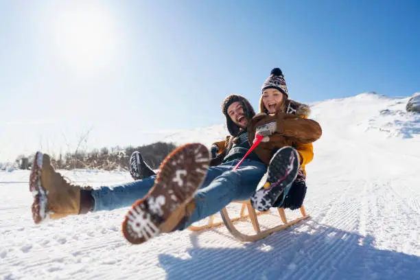 Young couple in love sledding and having fun on the snow.