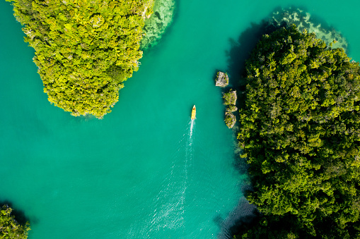 High angle shot of a boat cruising around the beautiful green islands of Indonesia
