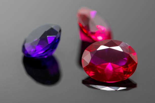 istock Red rubies and purple amethyst gemstones on black reflective surface 1202982362