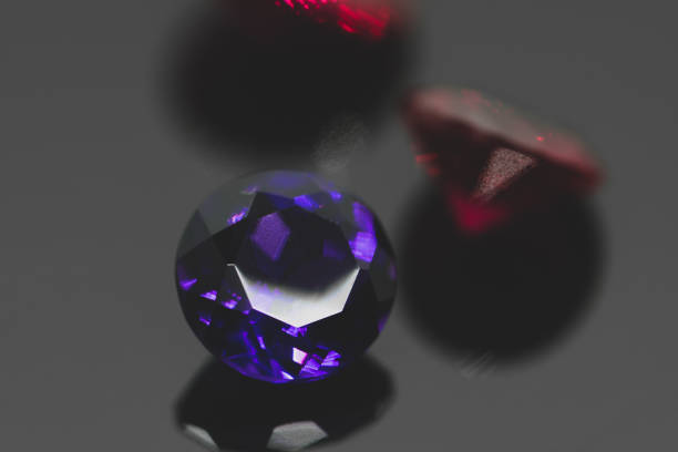 istock Purple amethyst gemstone and red rubies on black reflective surface 1202982363