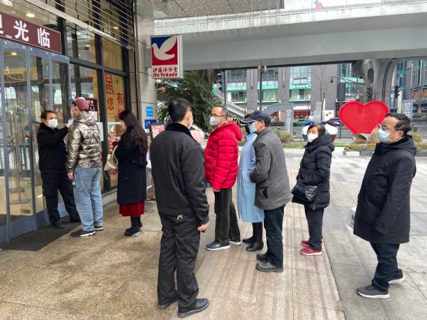 Wearing masks, people lined up for temperature checks before entering the mall in Chengdu,China stock photo