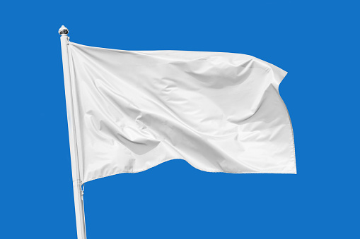 Bandera blanca ondeando en el viento en el asta de la bandera, aislado en el fondo azul photo