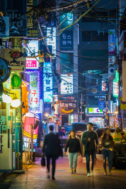 Seoul people on busy nightlife street Sinchon neon night Korea People walking through the neon lit night streets of Sinchon in the heart of Seoul, South Korea’s vibrant capital city. kangnamgu stock pictures, royalty-free photos & images