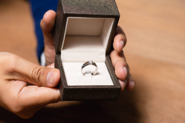 istock Close up of man hands holding ring box with wedding ring. 1202994729