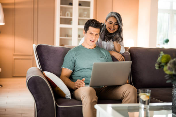istock Happy mature man using laptop in living room 1203001952