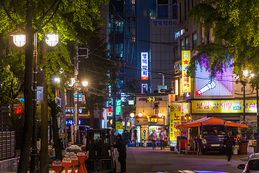 Shoppers and workers walking through the busy streets of Myeong-Dong illuminated at night in the heart of Seoul, South Korea’s vibrant capital city.