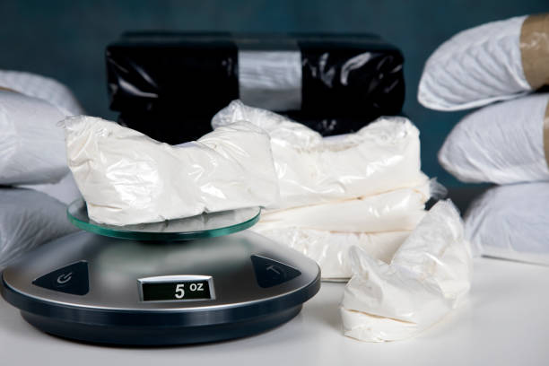 Illegal drugs on a scale measuring five ounces Confiscated illegal substance with measuring scale indicating 5 ounces, and a briefcase full of American currency. cocaine photos stock pictures, royalty-free photos & images