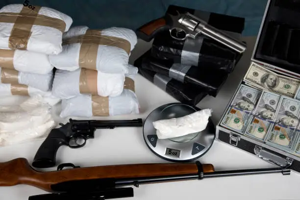 Photo of Illegal drugs on a scale with money, and guns