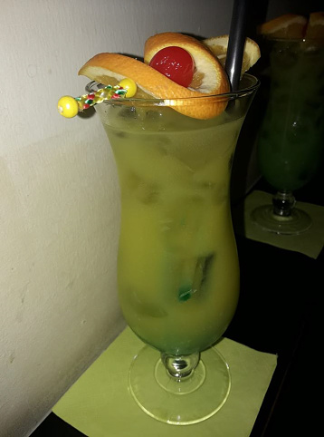 a green cocktail with an orange on the top