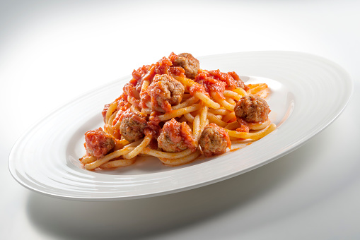 Plate of spaghetti with tomato and meatballs on white background