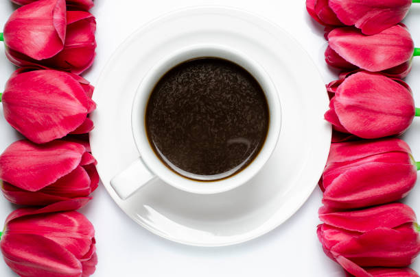istock A cup of black coffee with red tulips on a white background 1203009430