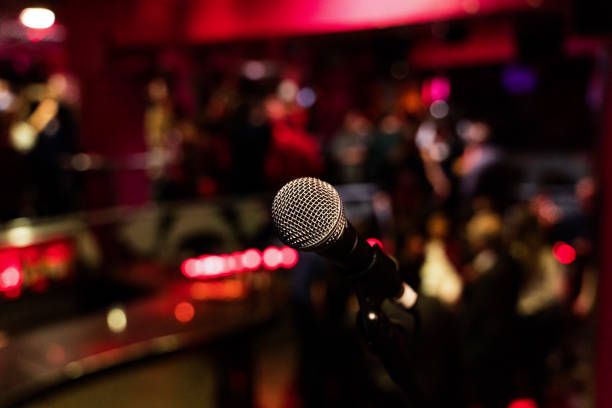 istock microphone on a stand up comedy stage with colorful bokeh, high contrast image. 1203014081