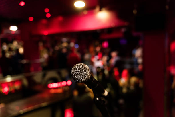 istock microphone on a stand up comedy stage with colorful bokeh, high contrast image. 1203014099