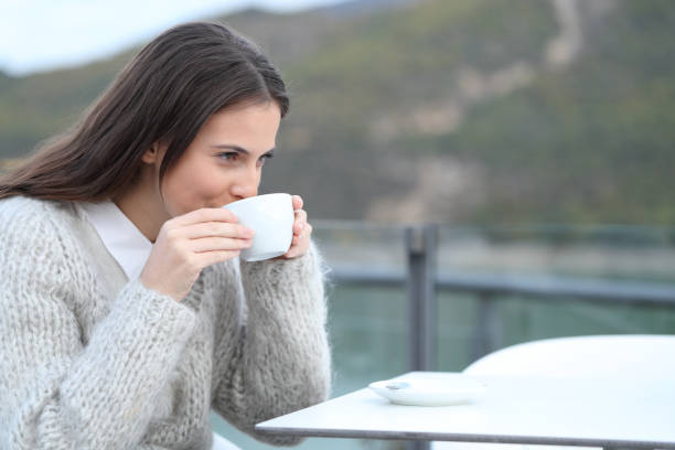 istock Happy girl drinking hot coffee in a restaurant terrace 1203015221