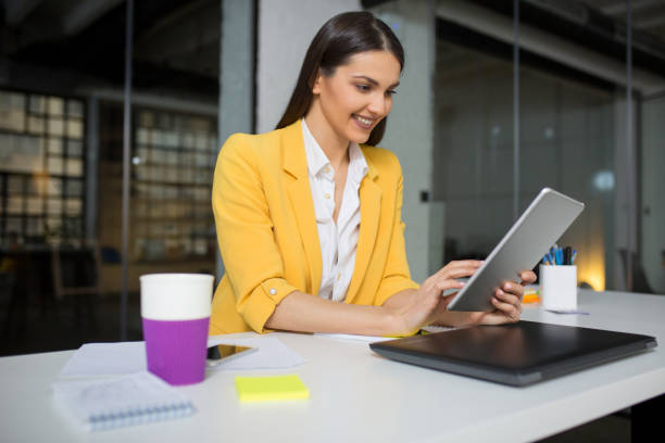 istock Cheerful businesswoman sitting and working on digital tablet 1203015334