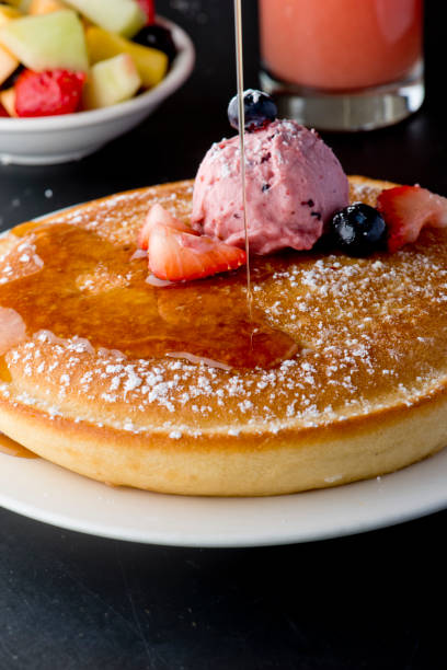 istock Pancakes, topped with fresh fruits and maple syrup 1203015654