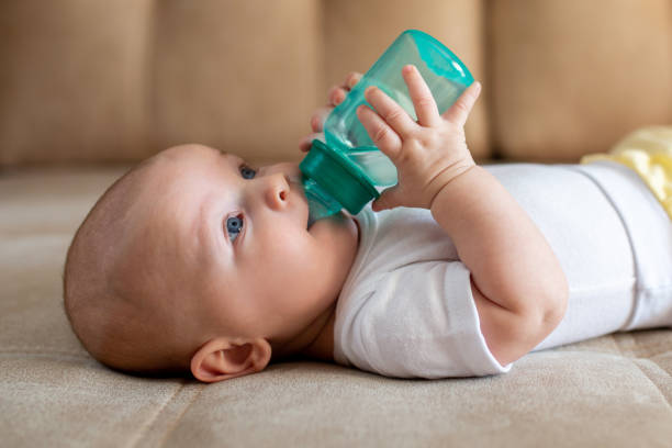 Cute boy child drinks water alone from a bottle with nipple.
