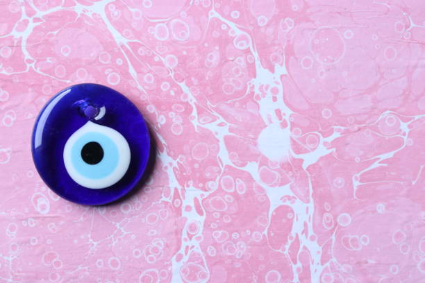 istock Blue evil eye, nazar bead on a pink marble ebru background 1203015899