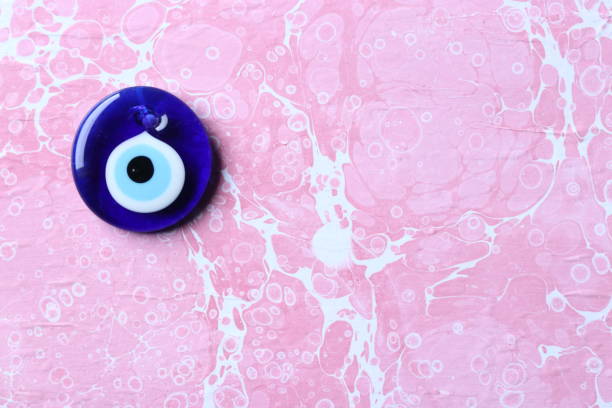 istock Blue evil eye, nazar bead on a pink marble ebru background 1203015900
