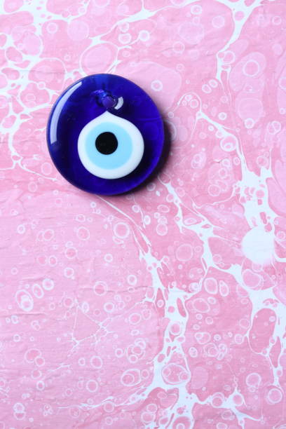 istock Blue evil eye, nazar bead on a pink marble ebru background 1203015909