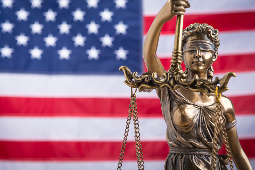 La estatua de la justicia Themis o Justitia, la diosa de los ojos vendados de la justicia contra una bandera de los Estados Unidos de América, como un concepto legal photo