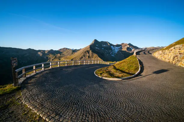 empty curvy mountain high alpine road with cobblestones in austrian alps on sunny late summer day with clear blue sky