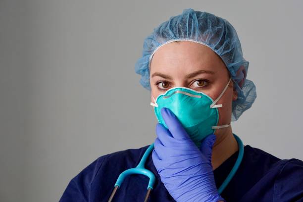 Close up of a female nurse putting on a respirator N95 mask to protect from airborne respiratory diseases such as the flu, coronavirus, ebola, TB, etc stock photo
