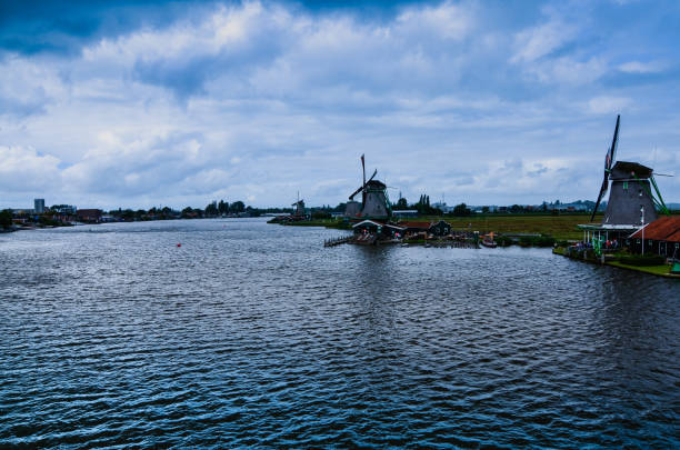 Zaanse Schans, Holland, August 2019. Northeast Amsterdam is a small community located on the Zaan River. View of the mills on the river bank, they stand out with their bright colors. Cloudy day.