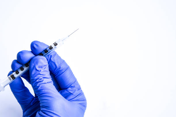 istock Hand in blue glove holding insulin syringe isolated on white background, Copy space 1203024460