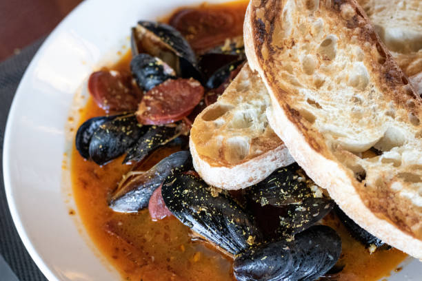 PEI Mussels PEI Mussels in red sauce with sourdough bread and red wine dre stock pictures, royalty-free photos & images