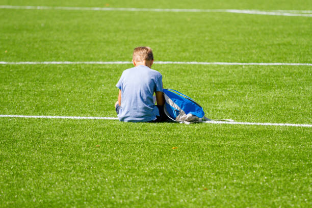 istock Sad alone boy with backpack sitting stadium outdoors 1203026479