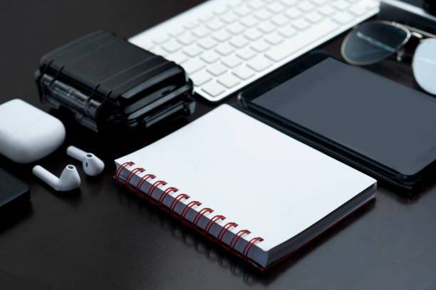 istock office table, with technology, white notebook, with red detail, headphones, waterproof case, computer keyboard, black tablet and sunglasses, black background 1203026511