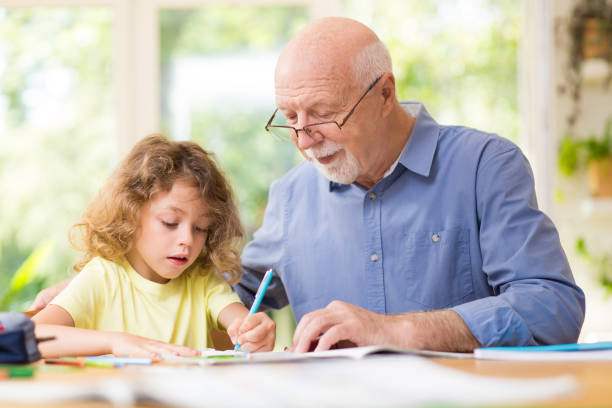 istock Grey grandfather and his cute grandson do homework 1203029012